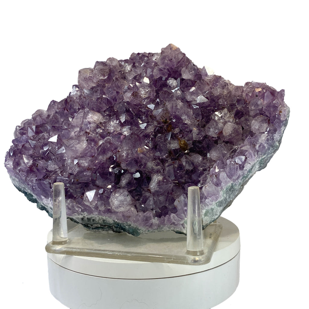 Rich amethyst cluster from South America with cacoxenite inclusions on white background