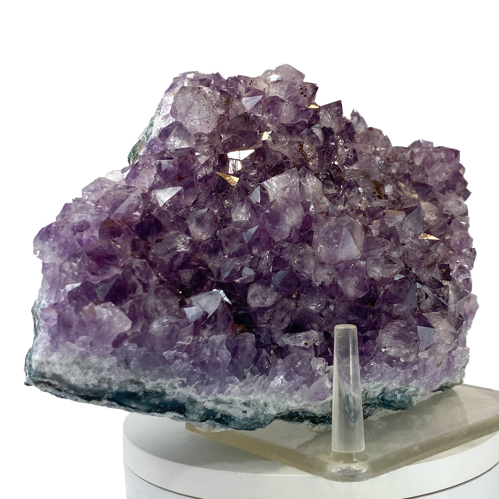 Rich amethyst cluster from South America with cacoxenite inclusions on white background