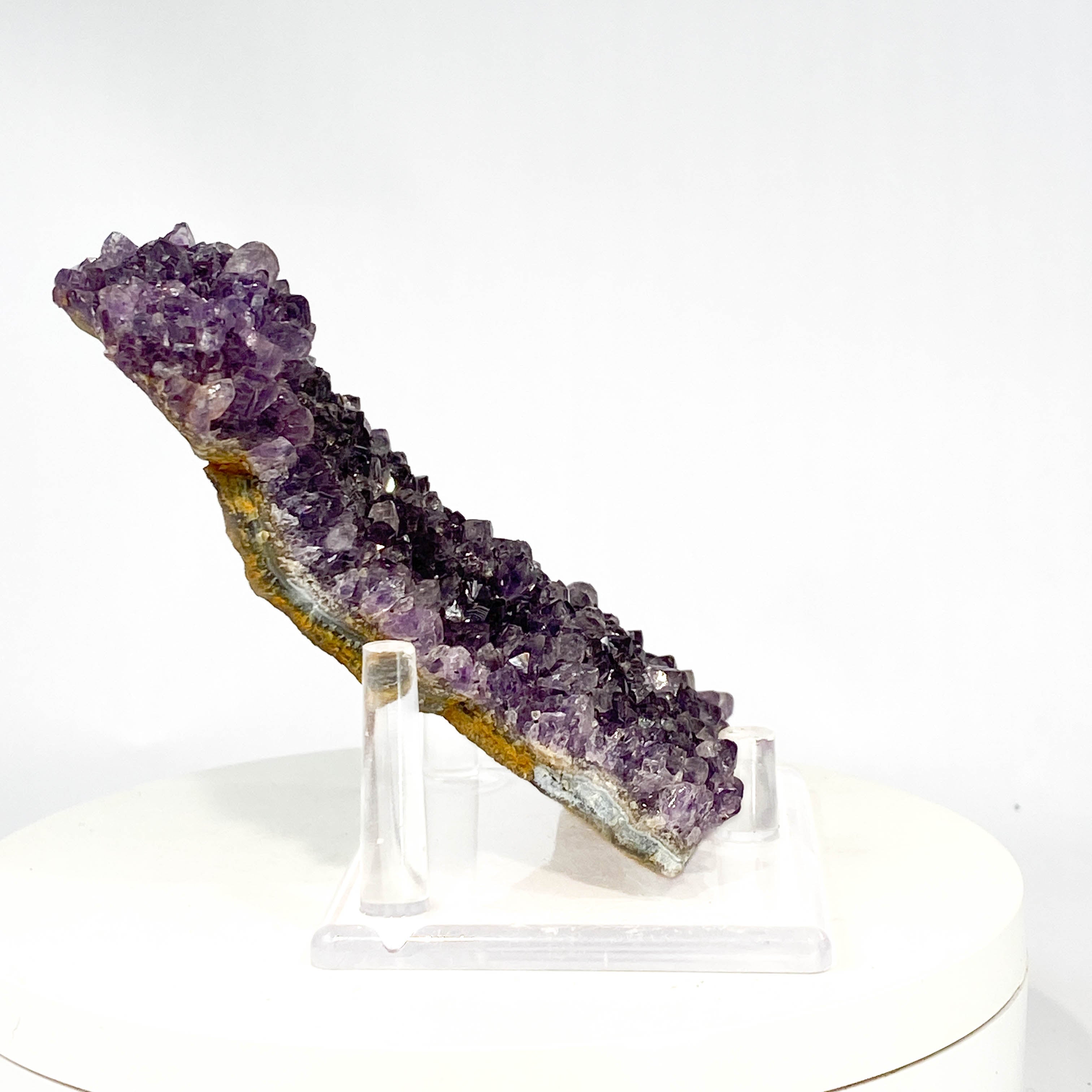 Dark purple amethyst cluster with fine crystal points on white background