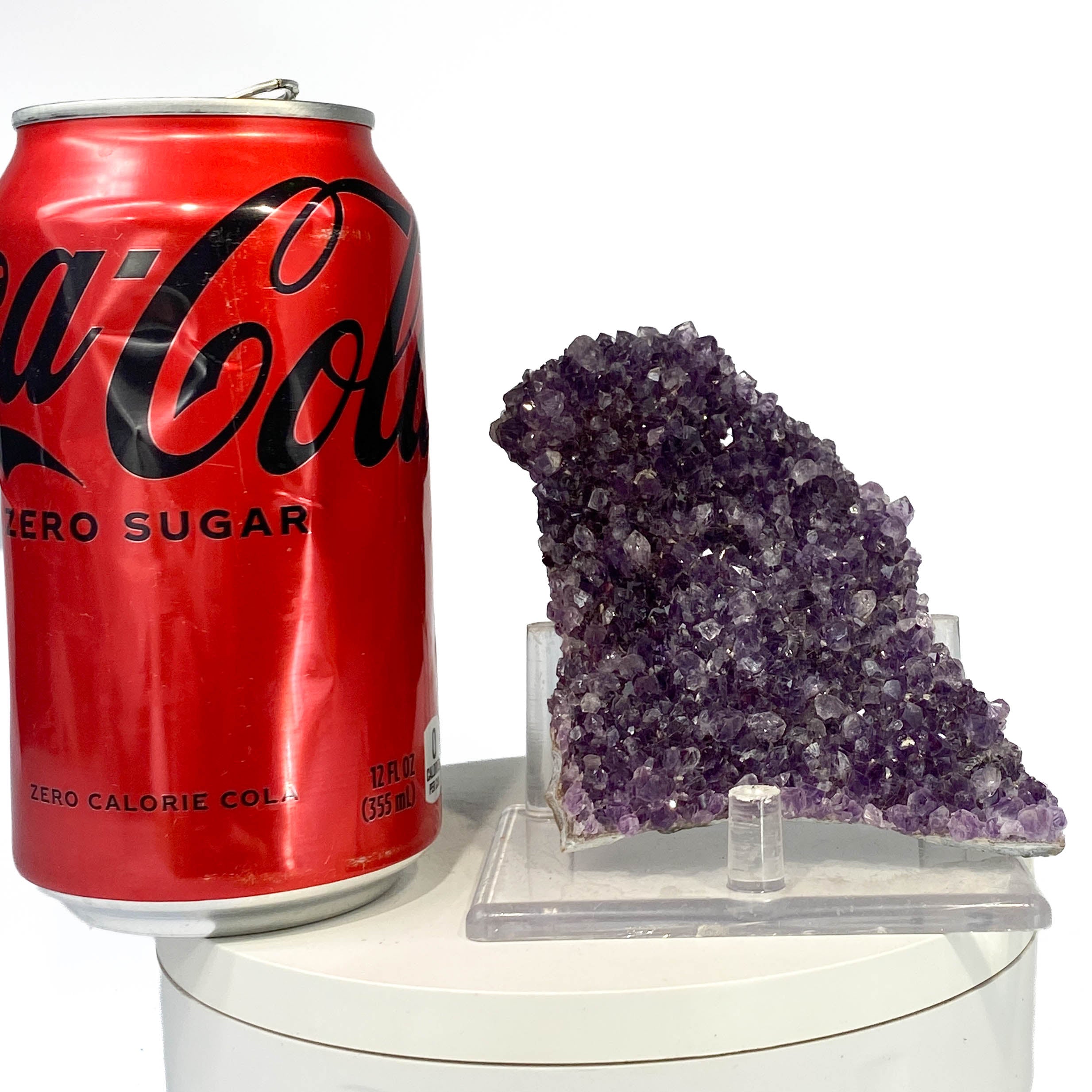 Dark purple amethyst cluster with fine crystal points, a soda can for scale