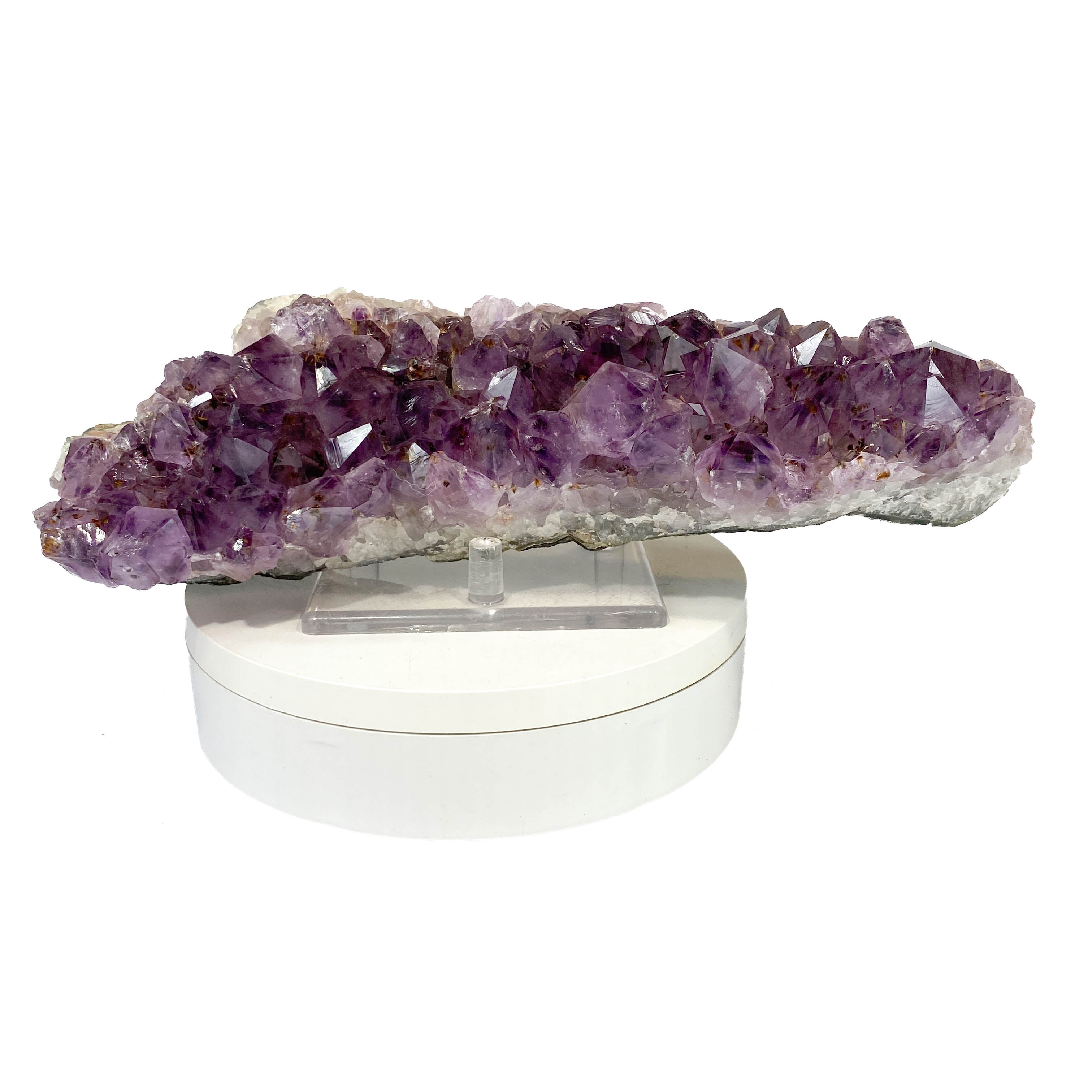 Elongated amethyst cluster with clear, iron-included crystals on white background