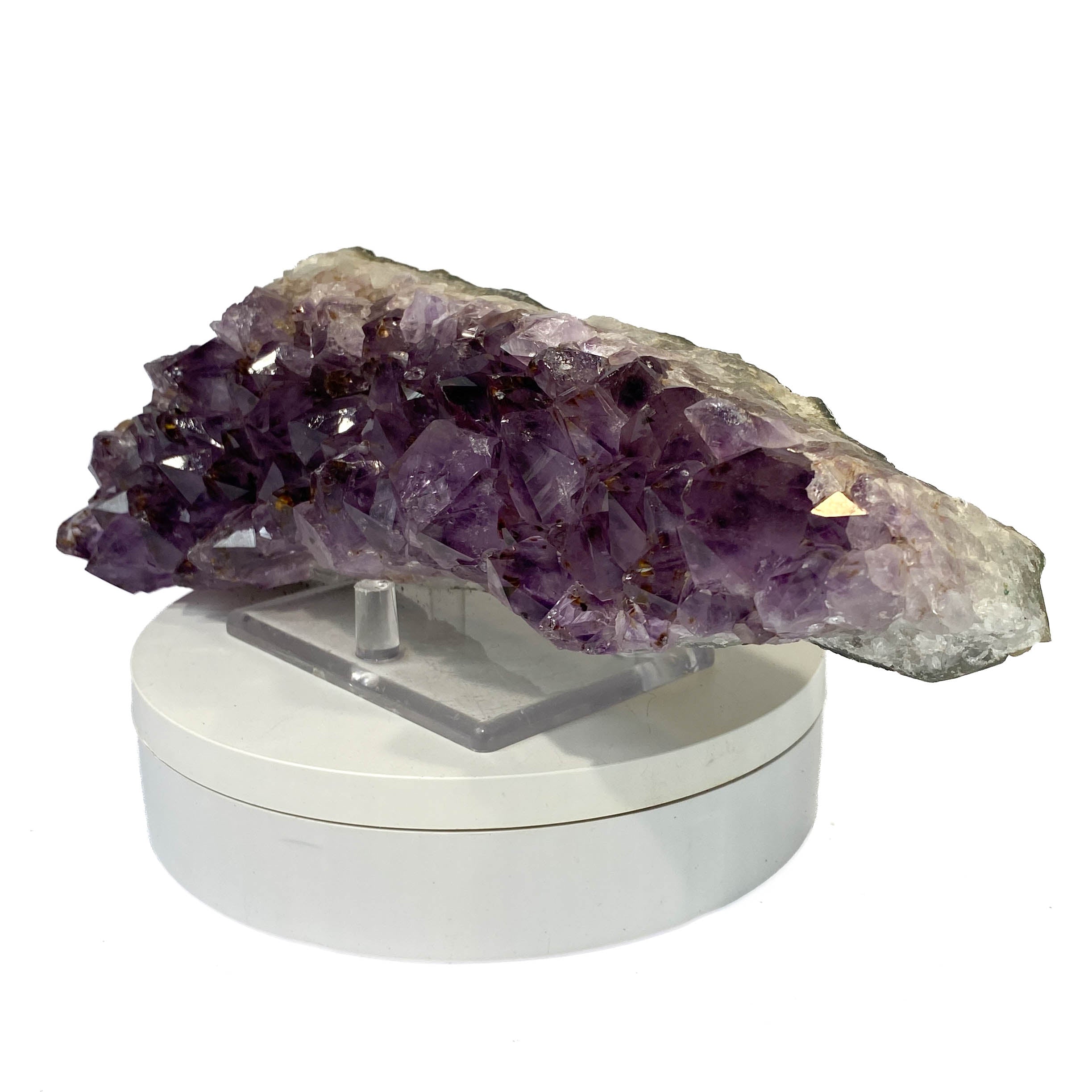 Elongated amethyst cluster with clear, iron-included crystals on white background