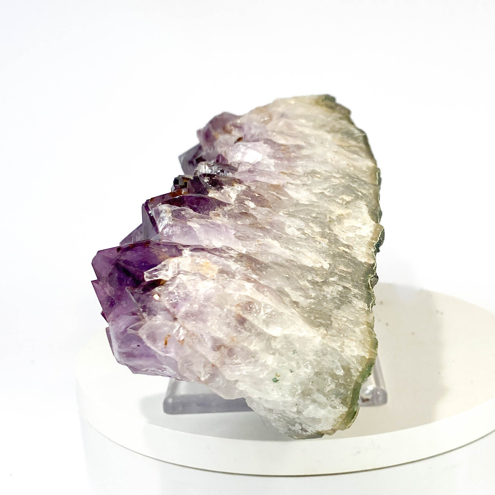 Elongated amethyst cluster with clear, iron-included crystals on white background