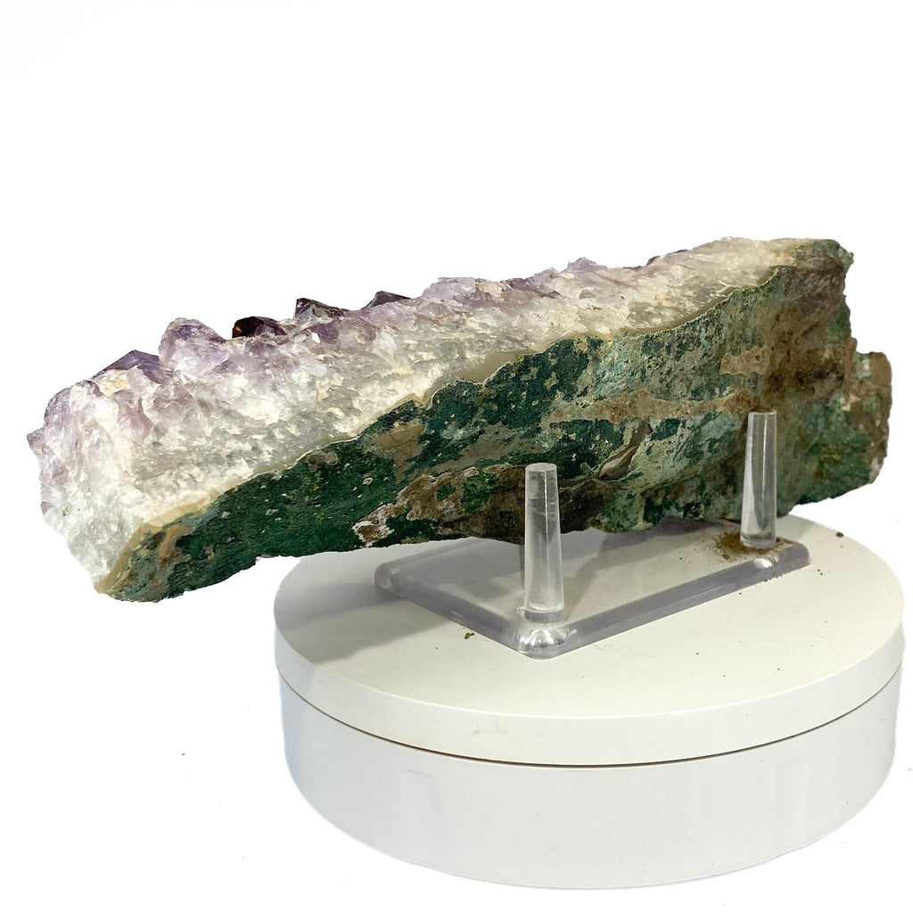 Elongated amethyst cluster with clear, iron-included crystals on white background