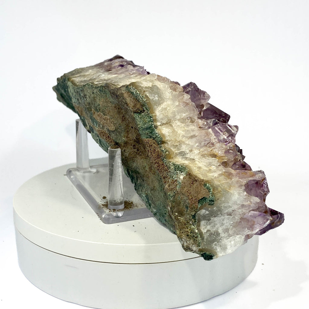 Elongated amethyst cluster with clear, iron-included crystals on white background