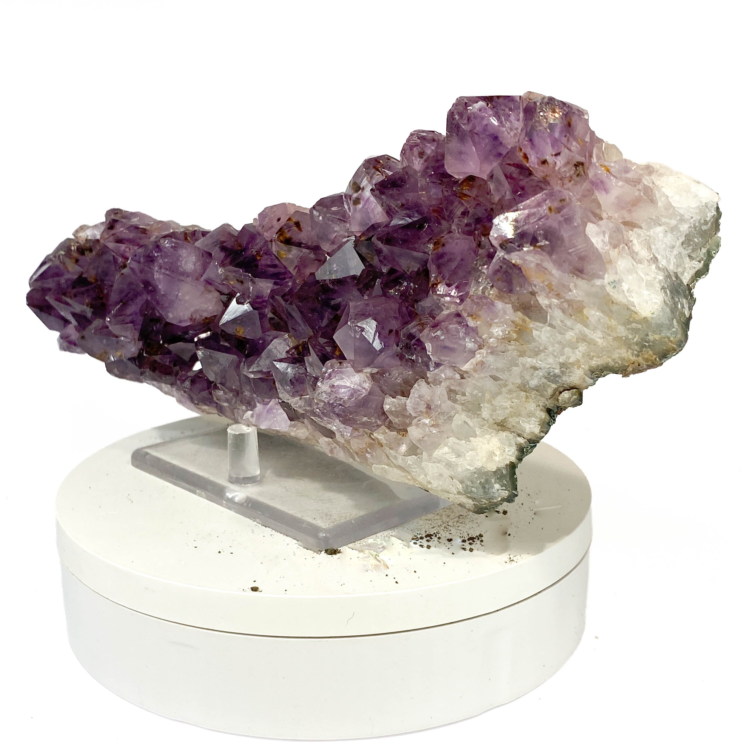Elongated amethyst cluster with clear, iron-included crystals on white background