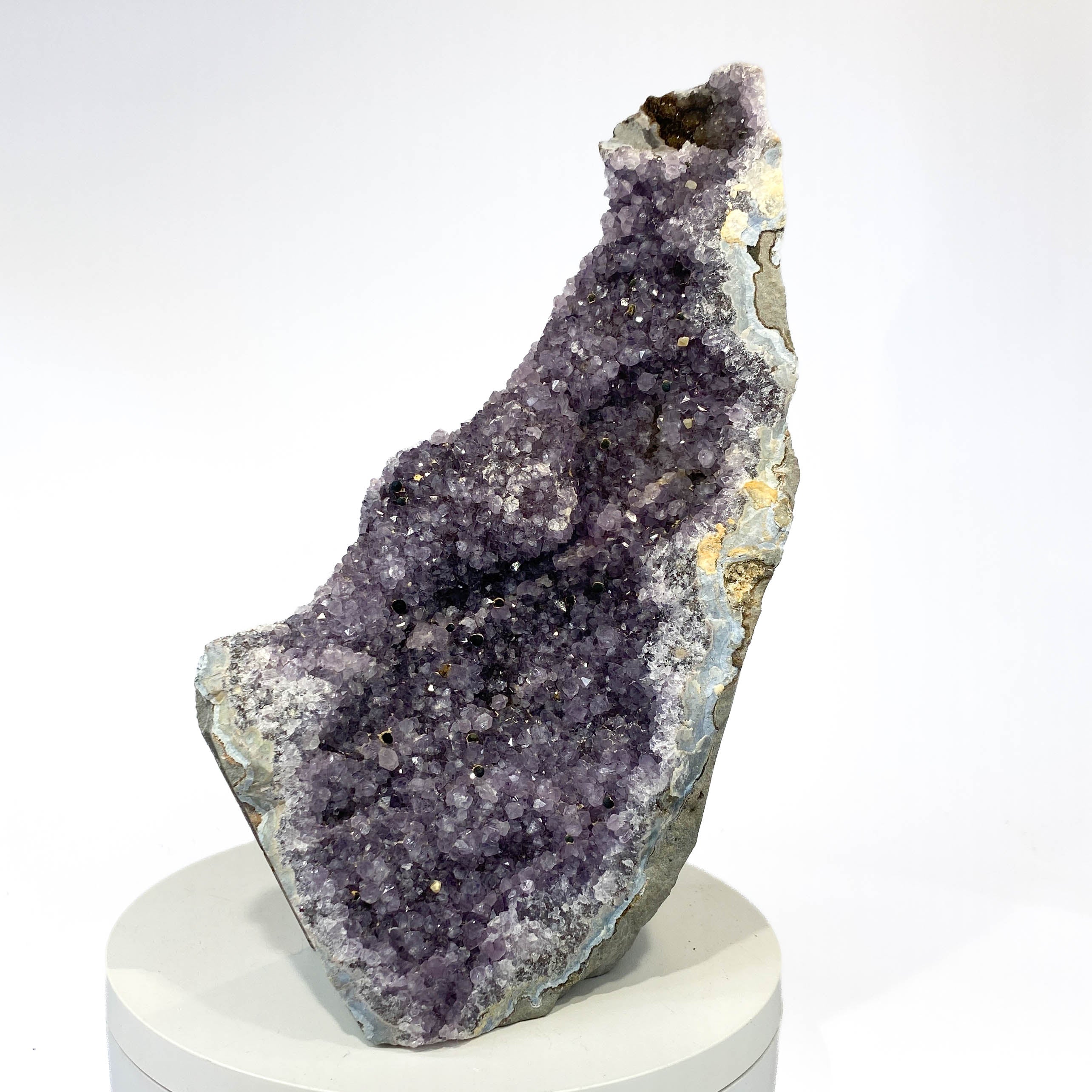 Standing deep amethyst cluster with black nodule inclusions on white background