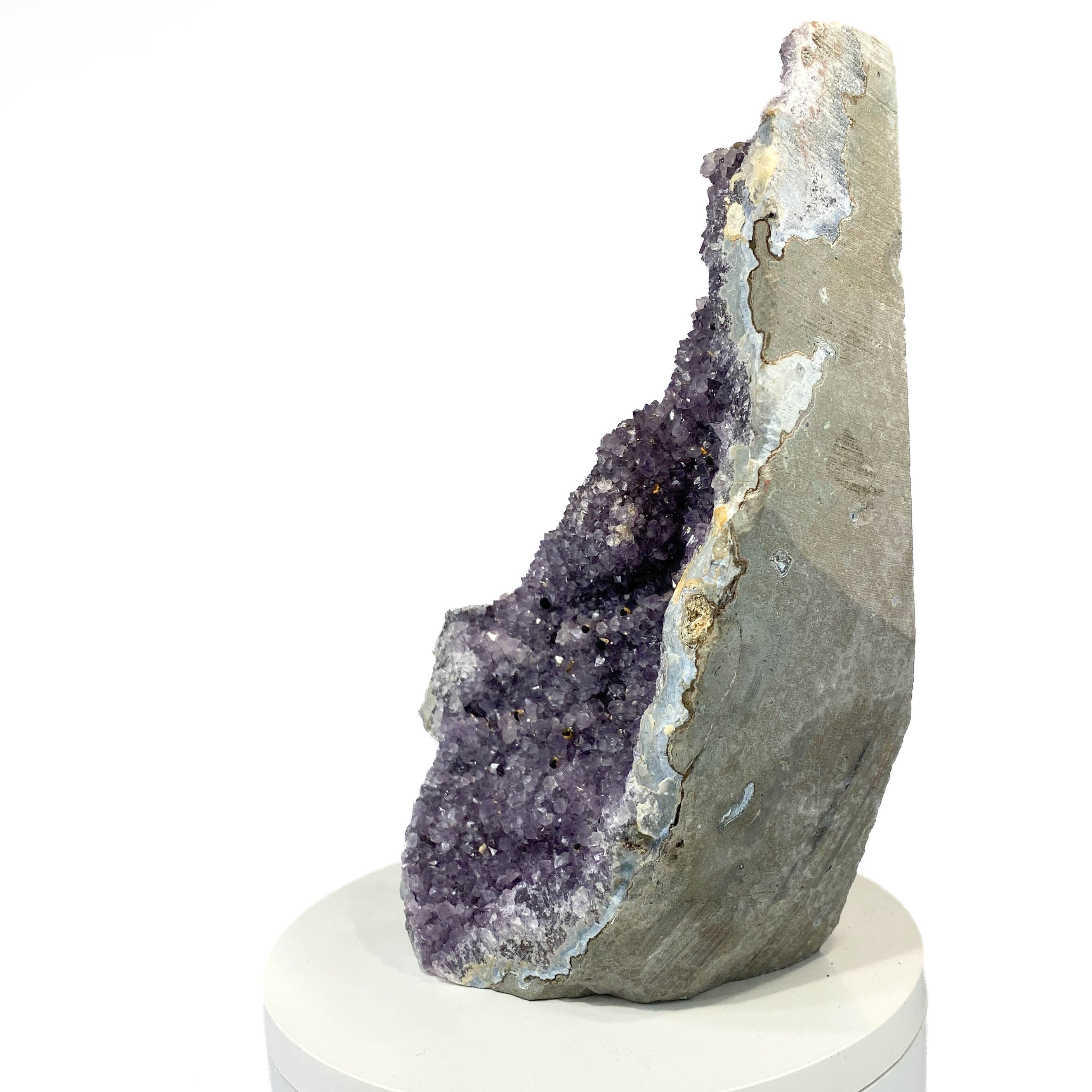 Standing deep amethyst cluster with black nodule inclusions on white background