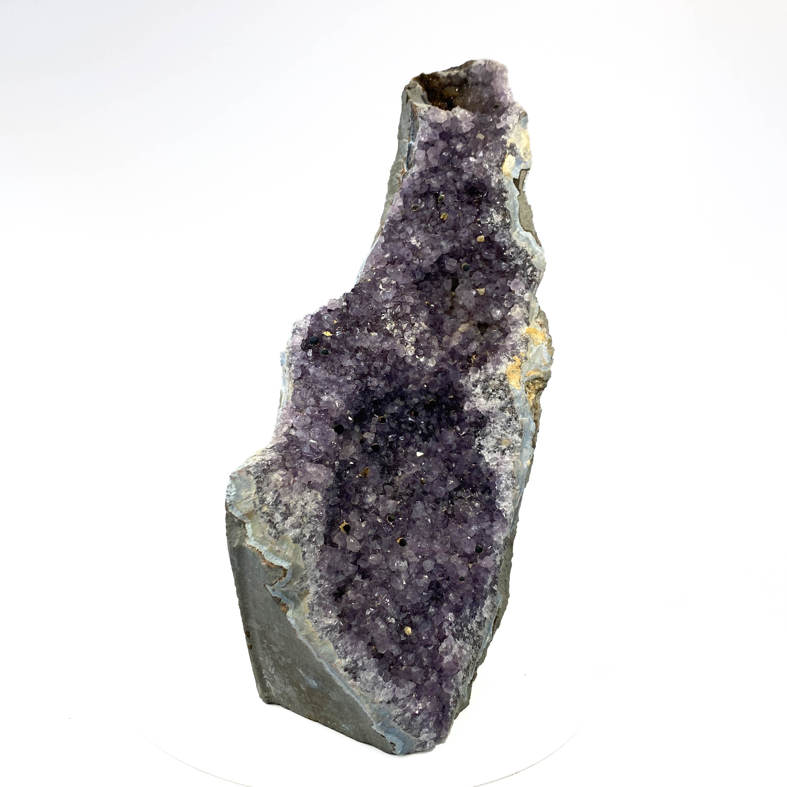 Standing deep amethyst cluster with black nodule inclusions on white background