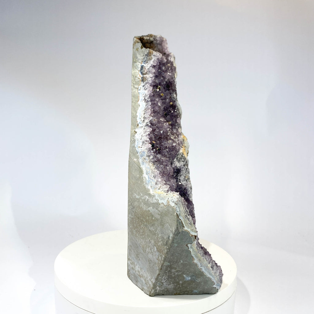 Standing deep amethyst cluster with black nodule inclusions on white background