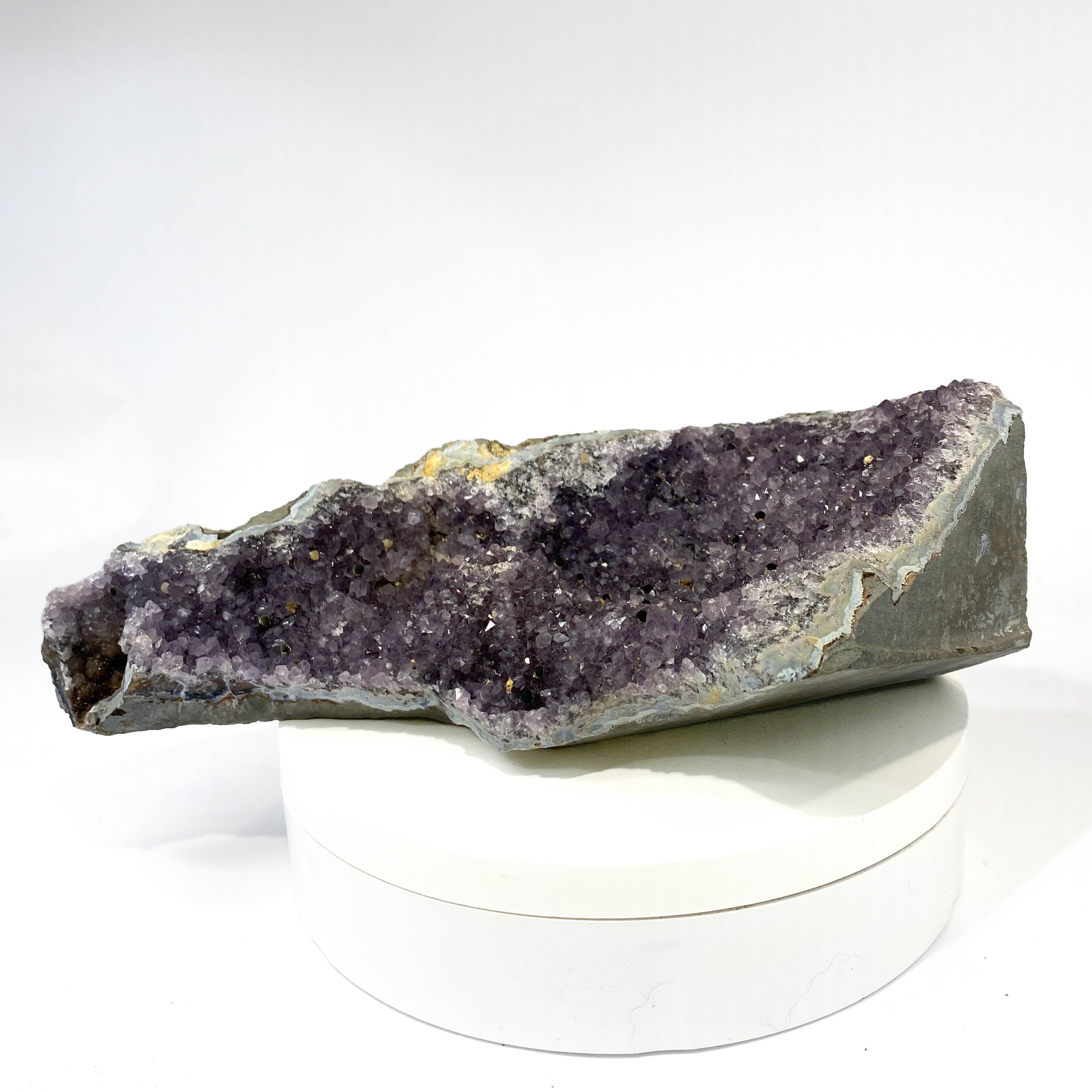 Standing deep amethyst cluster with black nodule inclusions on white background