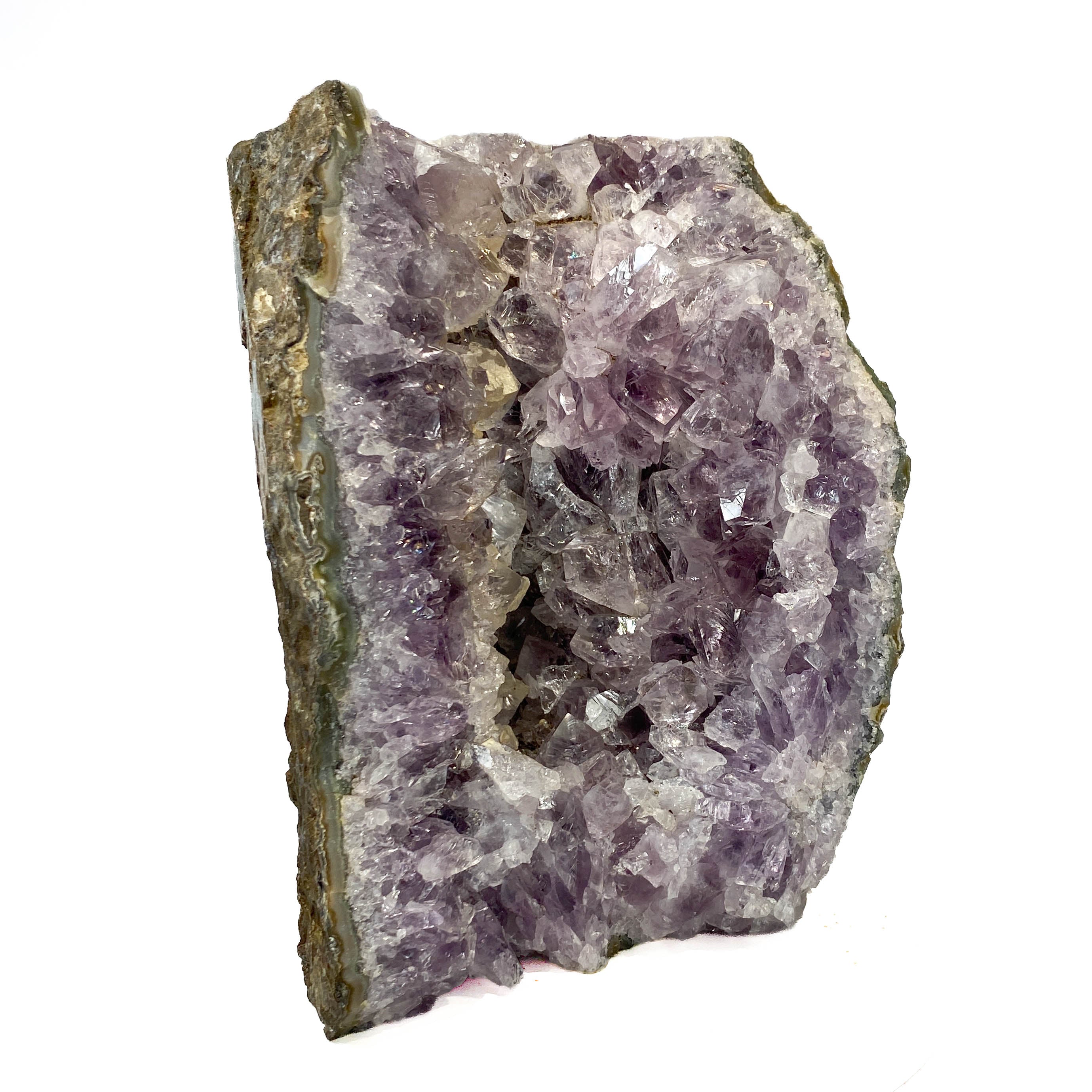 A raw amethyst geode specimen with a purple crystal cavity and a rough, earthy brown and gray outer matrix, shown on a plain white background.