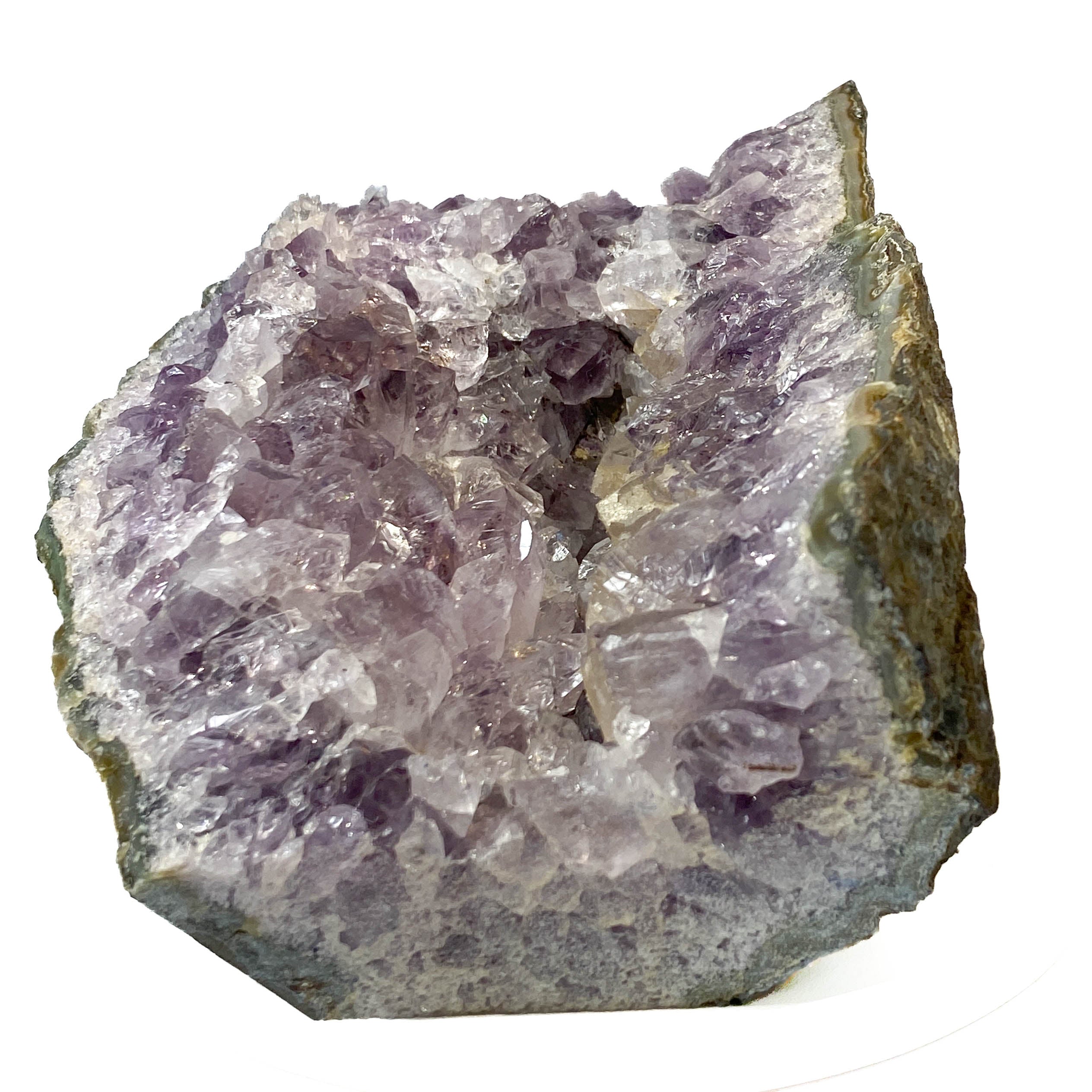 A raw amethyst geode specimen with a dense cluster of purple and clear quartz crystals on an irregular, rough matrix, isolated on a white background.