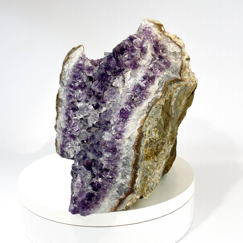 Standing angel-shaped amethyst cluster with dark crystals and phantoms on white background