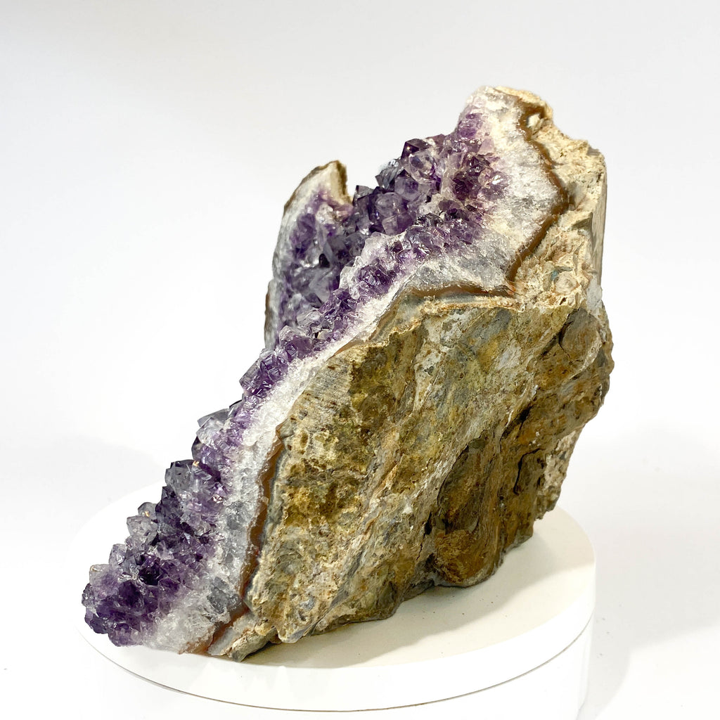 Standing angel-shaped amethyst cluster with dark crystals and phantoms on white background
