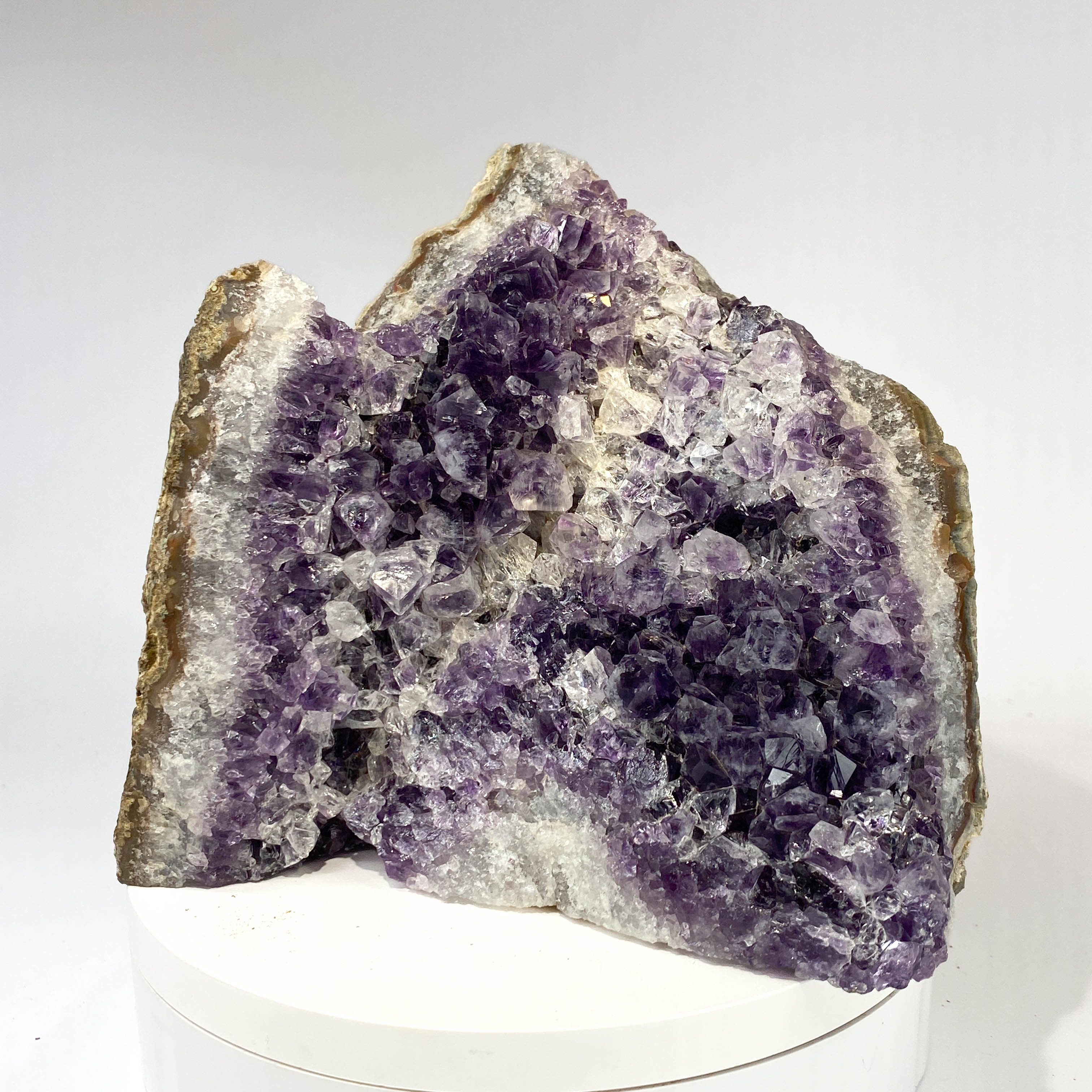 Standing angel-shaped amethyst cluster with dark crystals and phantoms on white background