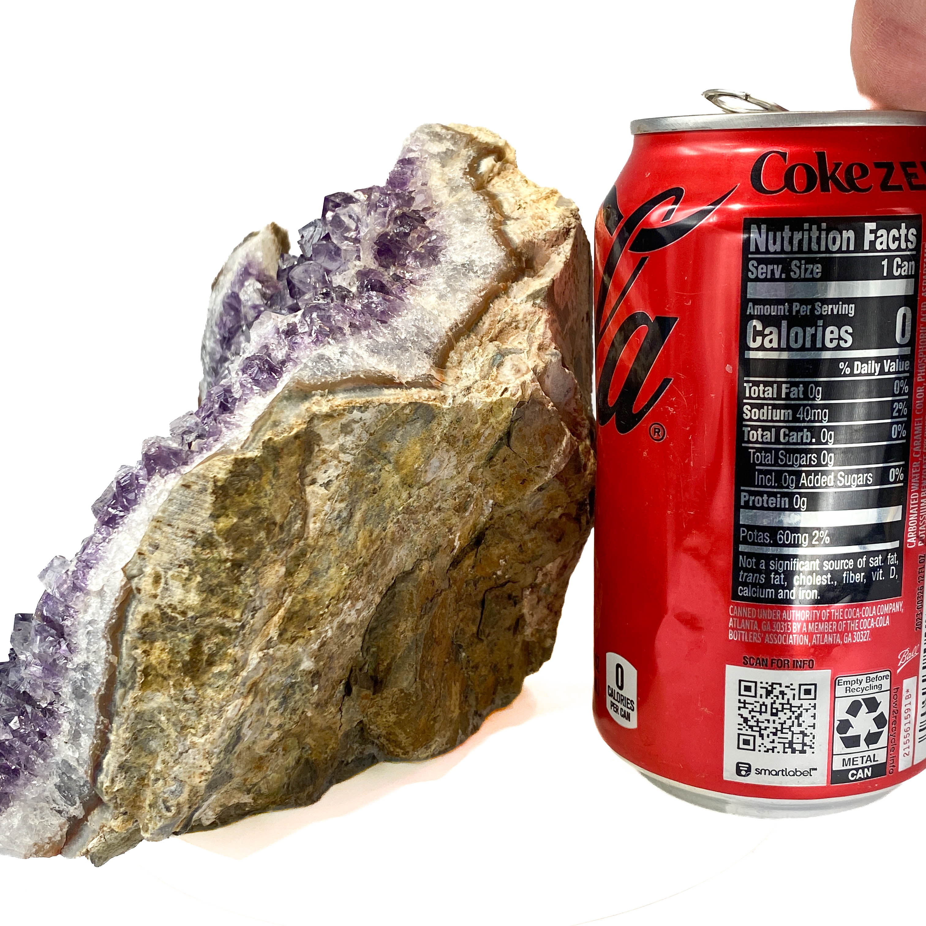 Standing angel-shaped amethyst cluster with dark crystals and phantoms, a soda can for scale