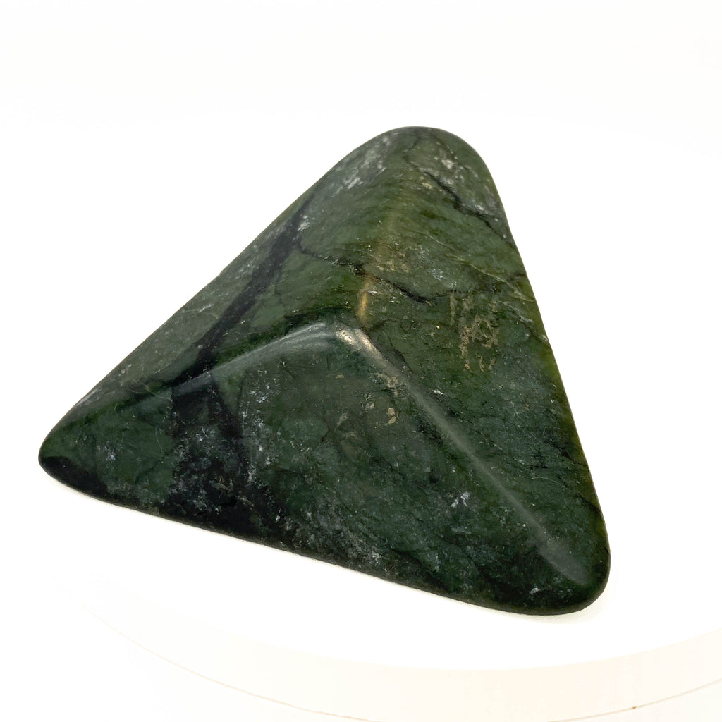 Carved Washington jade triangle with tree pattern on white background