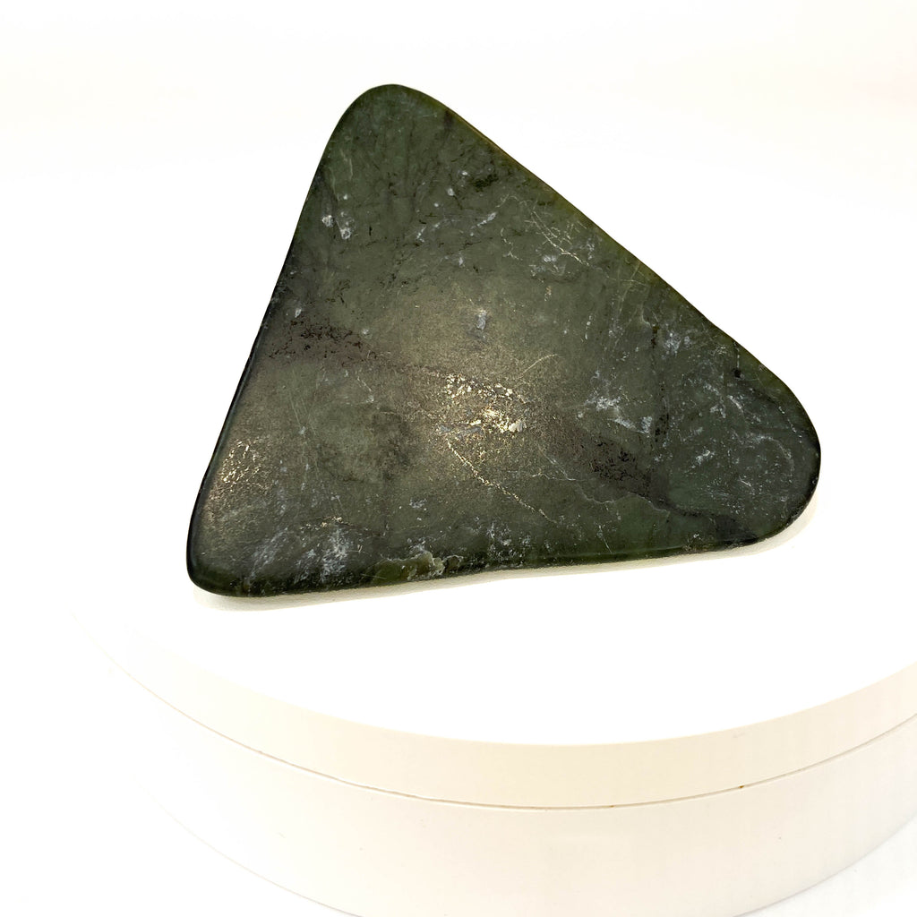 Carved Washington jade triangle with tree pattern on white background