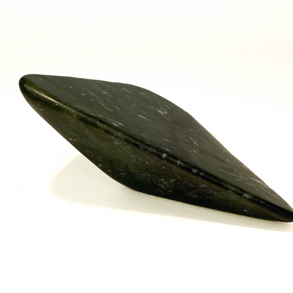 Carved Washington jade triangle with tree pattern on white background