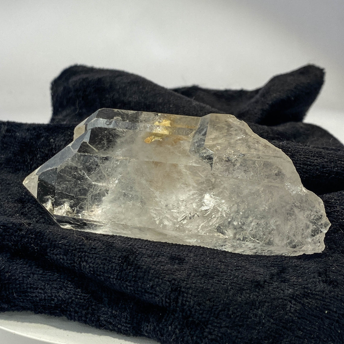Tantric twin quartz crystal with rainbow refractions on black cloth background