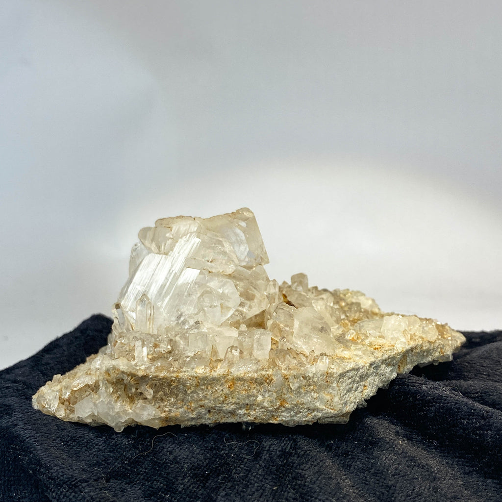 Double-sided quartz plate with clear crystal cluster on dark cloth background