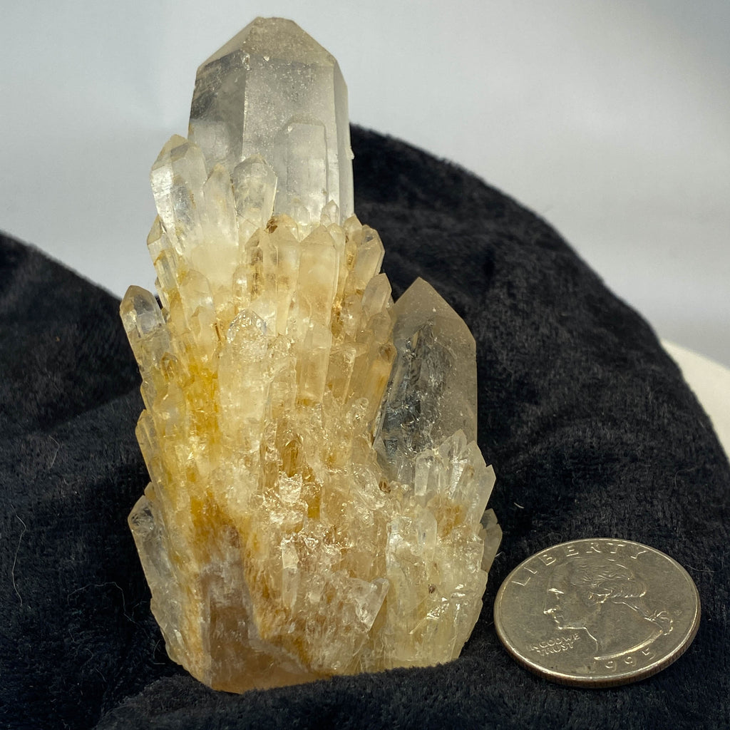 Clear candle quartz crystal cluster with daughter crystals on black cloth background