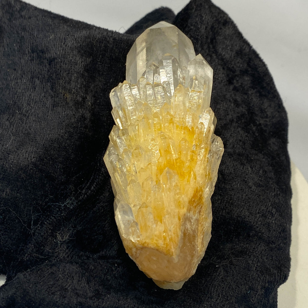 Clear candle quartz crystal cluster with daughter crystals on black cloth background