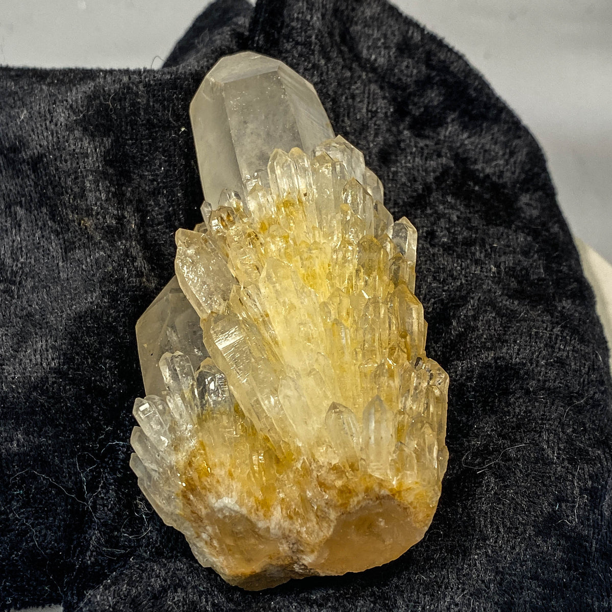 Clear candle quartz crystal cluster with daughter crystals on black cloth background