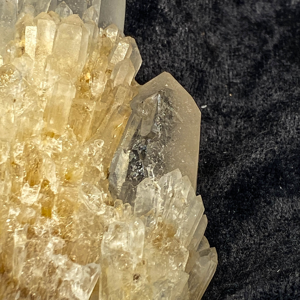 Clear candle quartz crystal cluster with daughter crystals on black cloth background