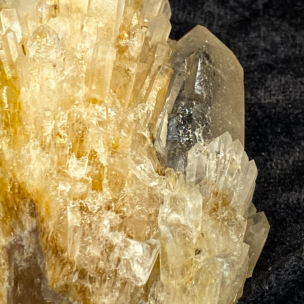 Clear candle quartz crystal cluster with daughter crystals on black cloth background
