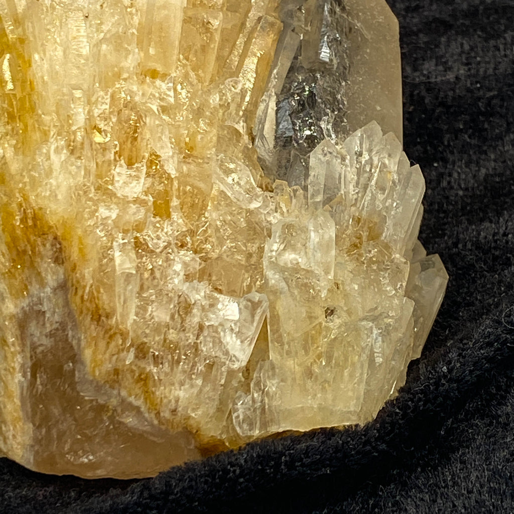 Clear candle quartz crystal cluster with daughter crystals on black cloth background