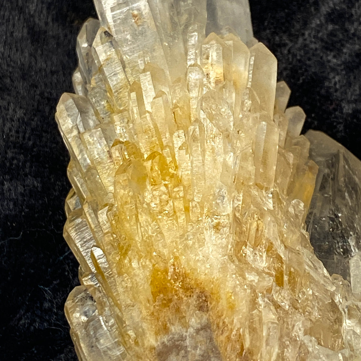 Clear candle quartz crystal cluster with daughter crystals on black cloth background