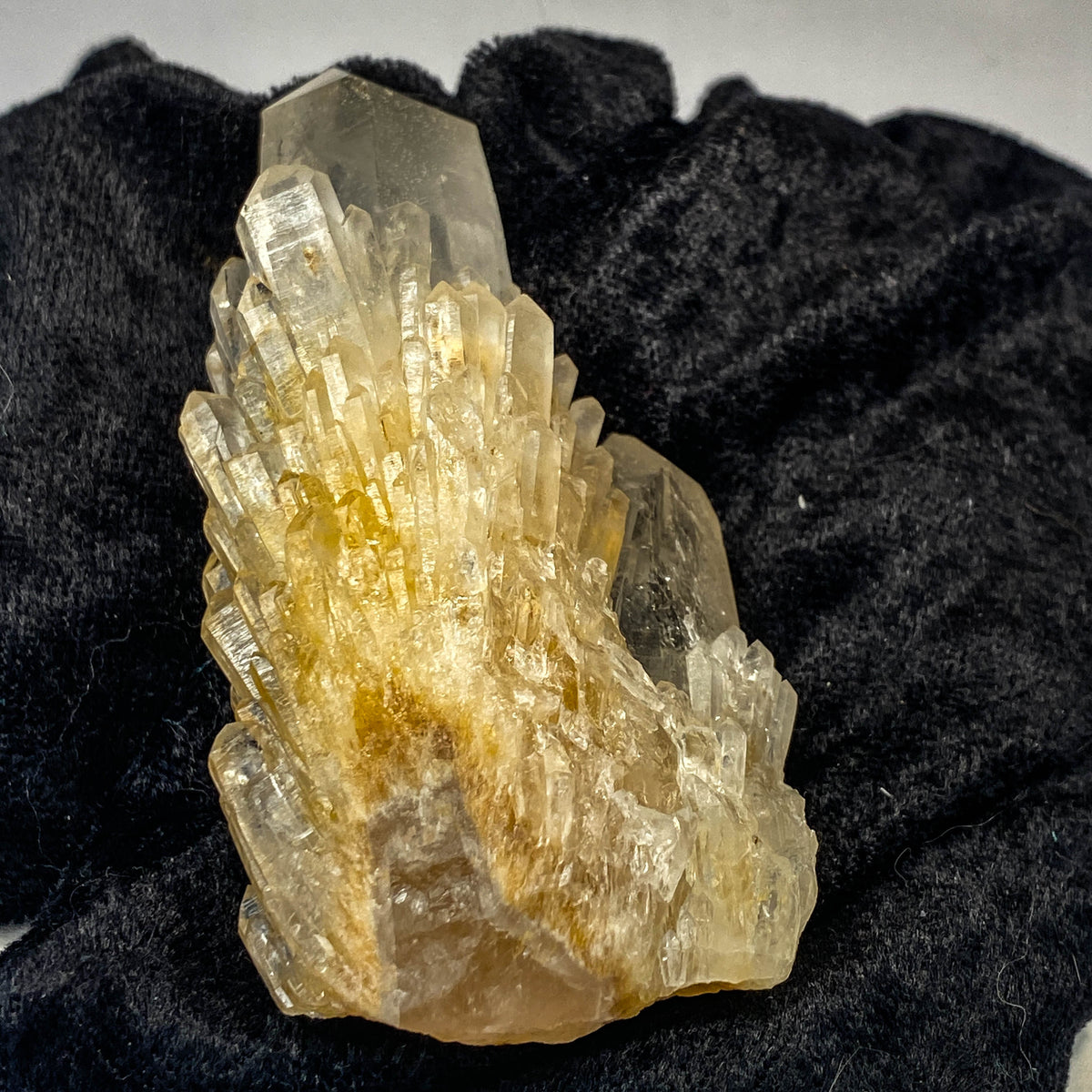 Clear candle quartz crystal cluster with daughter crystals on black cloth background