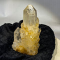 Clear candle quartz crystal cluster with daughter crystals on black cloth background
