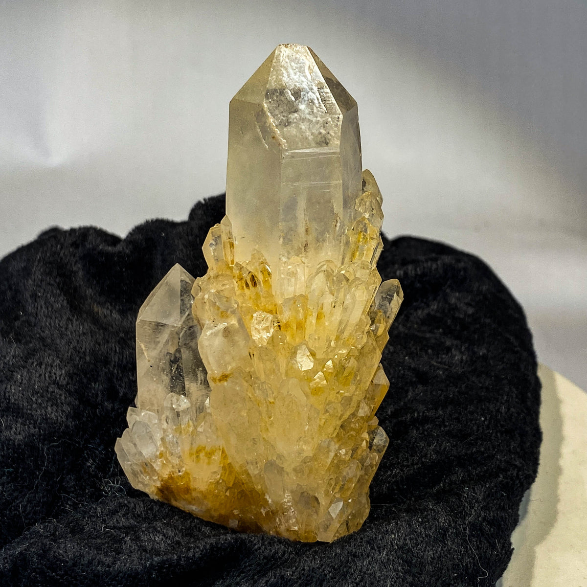Clear candle quartz crystal cluster with daughter crystals on black cloth background