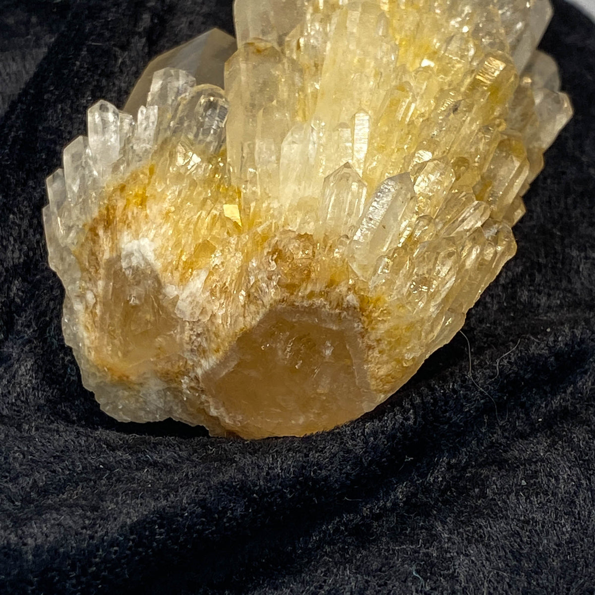 Clear candle quartz crystal cluster with daughter crystals on black cloth background