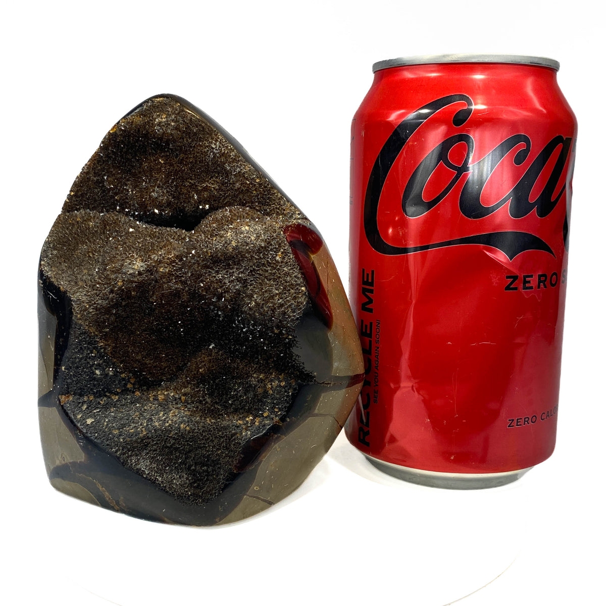 Septarian nodule with brown-black druzy pocket on white background